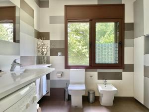 baño con aseo y lavabo y ventana en Can Baseia - amb jardí i accés privat a La Fageda, en Santa Pau