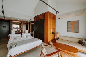 een slaapkamer met een groot bed en een bank bij The Komu in Canggu