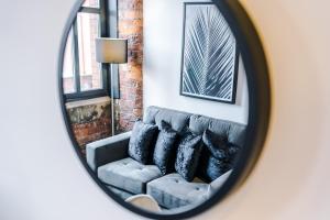 a mirror reflecting a couch in a living room at Meadow Mill by Staycay in Stockport