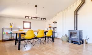 comedor con mesa, sillas amarillas y chimenea en Can Blanc de Montagut, en Montagut
