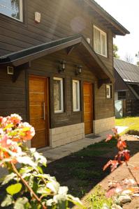 una casa con puertas de madera y flores delante de ella en Cabañas lo de Ani Casa 1 en San Carlos de Bariloche