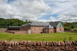 a large brick house in a field with a stone wall at Dryburgh Steading Three in Saint Boswells