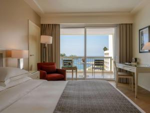 um quarto de hotel com uma cama, uma secretária e uma varanda em Mövenpick Hotel Beirut em Beirute