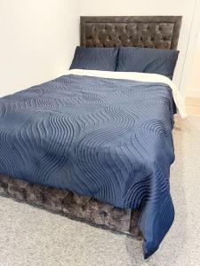 a bed with a blue comforter and pillows at Luxury 3 Bedroom House in Worthing