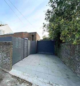 a fence with a blue gate and a brick wall at Luxury 3 Bedroom House in Worthing