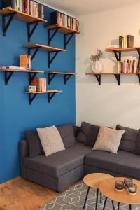 a living room with a couch and shelves on the wall at Főtér Apartman in Kiskunhalas