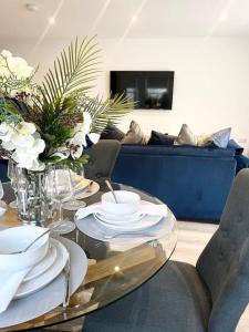 un comedor con una mesa de cristal con platos y flores en Luxury 3 Bedroom House, en Worthing