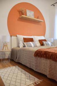 um quarto com uma cama com uma parede laranja em Főtér Apartman em Kiskunhalas