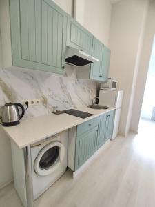 ポルタヴァにあるApartment Smartのキッチン(緑のキャビネット、洗濯機付)