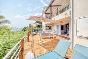 a house with a deck with chairs and an umbrella at Villa Kap Grand Large in Saint-Leu