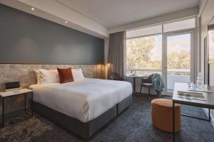 a hotel room with a large bed and a desk at Hotel Alba Adelaide in Adelaide