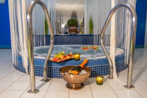 a tub with a bowl of fruit and a bottle of wine at Hotel Tommy Wellness & Spa in Náchod