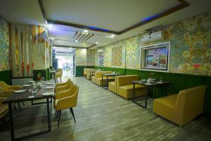 Q Saina S K Regency Rishikesh في ريشيكيش: غرفة طعام مع طاولات وكراسي صفراء وورق جدران