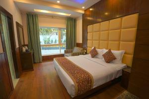 a hotel room with a bed and a window at Q Saina S K Regency Rishikesh in Rishīkesh