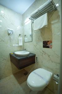 a bathroom with a white toilet and a sink at Q Saina S K Regency Rishikesh in Rishīkesh