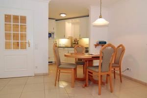 uma cozinha com uma mesa de madeira e cadeiras em Residenz Bismarck, Whg 11 em Westerland