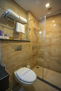 La salle de bains est pourvue de toilettes et d'une douche en verre. dans l'établissement Q Saina S K Regency Rishikesh, à Rishikesh