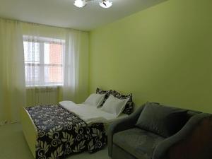 een slaapkamer met een bed, een stoel en een raam bij Центр Гостеприимства in Aqtöbe