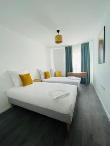 two beds in a hotel room with yellow pillows at Domitys L'Agapanthe in Lille