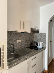 a kitchen with white cabinets and a sink at BuenaVista Torviscas Beach in Adeje