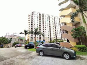 a car parked in a parking lot in front of a building at Tranquil Cool Studio Condo Mactan Cebu in Lapu Lapu City