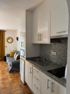 a kitchen with white cabinets and a sink and a couch at BuenaVista Torviscas Beach in Adeje