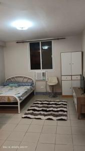 a bedroom with a bed and a microwave and windows at Tranquil Cool Studio Condo Mactan Cebu in Lapu Lapu City