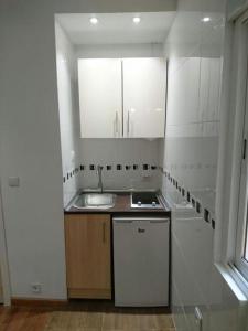 a kitchen with white cabinets and a sink and a window at Apartamentos EconoStay Barbieri 1 in Madrid