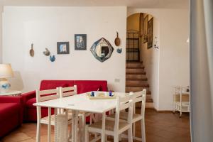 uma sala de estar com uma mesa branca e um sofá vermelho em Casa Isidora by Wonderful Italy em Arzachena