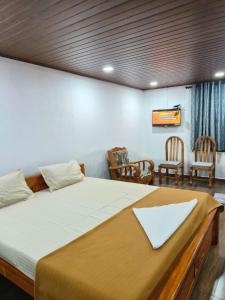 uma cama grande num quarto com duas cadeiras em Coorg view estate Homestay em Madikeri
