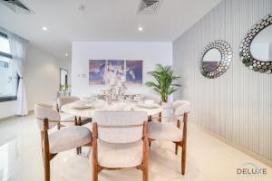 una sala da pranzo bianca con tavolo e sedie di Grand 4BR Villa with Assistant's and Driver's Room Al Dana Island Fujairah by Deluxe Holiday Homes a Fujaira
