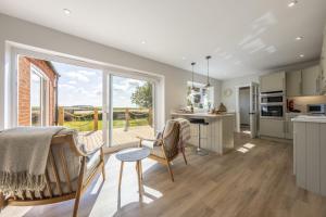 a kitchen with a table and chairs and a large window at Larks Rise in Burnham Market