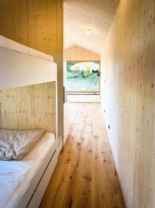 een slaapkamer met een bed en een houten vloer bij Die Klingerei - Tiny House Wiese in Pettighofen