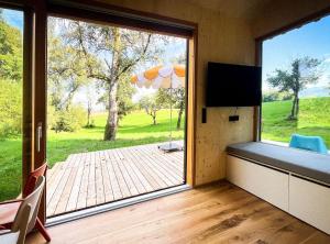 a room with a large window with a view of a deck at Die Klingerei - Tiny House Wiese in Pettighofen