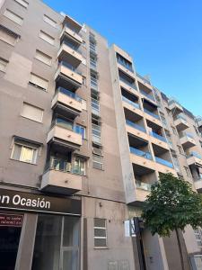 a tall apartment building with a tree in front of it at Piso en Gandía in Gandía