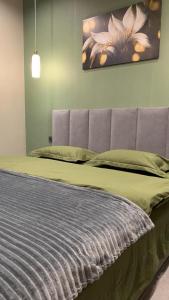 a bedroom with a bed with a green comforter at Апартаменты в Астане in Astana