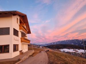 a building on a hill with a sunset in the background at Perchnerhof in Terento