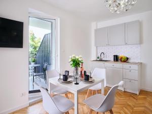 a white kitchen with a white table and chairs at Villa Łeba II - Loft Apartments in Łeba