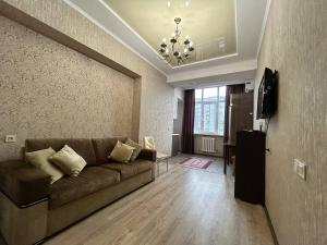 sala de estar con sofá y TV en AURA on Ryskulov street 30 en Bishkek