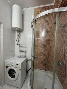 a bathroom with a shower and a washing machine at AURA on Ryskulov street 30 in Bishkek