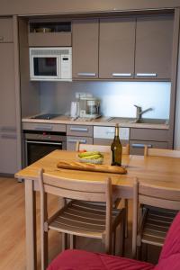 a kitchen with a wooden table with a bottle of wine at Azureva Métabief in Métabief