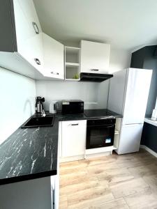 a kitchen with white cabinets and a black counter top at Panorama Apartment Kraków in Krakow