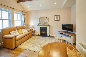 a living room with a couch and a television at Host & Stay - Gas Light Cottage in Ripon