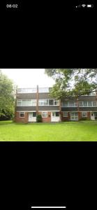 un grande edificio in mattoni con un prato di fronte di Ainsdale Gardens a Birmingham