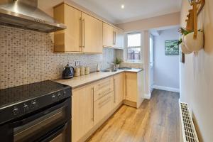 a kitchen with wooden cabinets and a sink and a stove at Host & Stay - Gas Light Cottage in Ripon