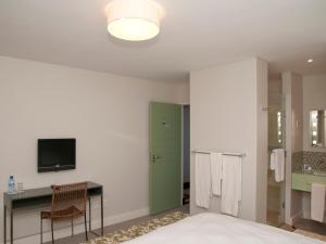 クニスナにあるCrow's Nestのベッドと机とテレビのある寝室