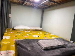 - une chambre avec un lit et une couverture jaune avec des vaches dans l'établissement Kim Hostel, à Hô-Chi-Minh-Ville
