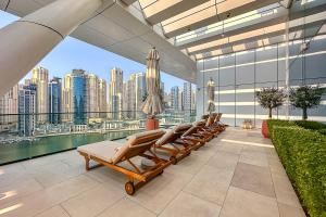 a row of lounge chairs on a balcony with a city skyline at Frank Porter - Vida Residences in Dubai