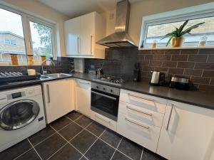 a kitchen with white cabinets and a washer and dryer at Ashvale, Cambridge in Chesterton