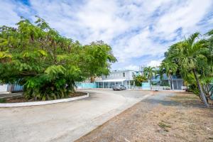 a driveway in front of a house with palm trees at West Coast Inn's in Rincon